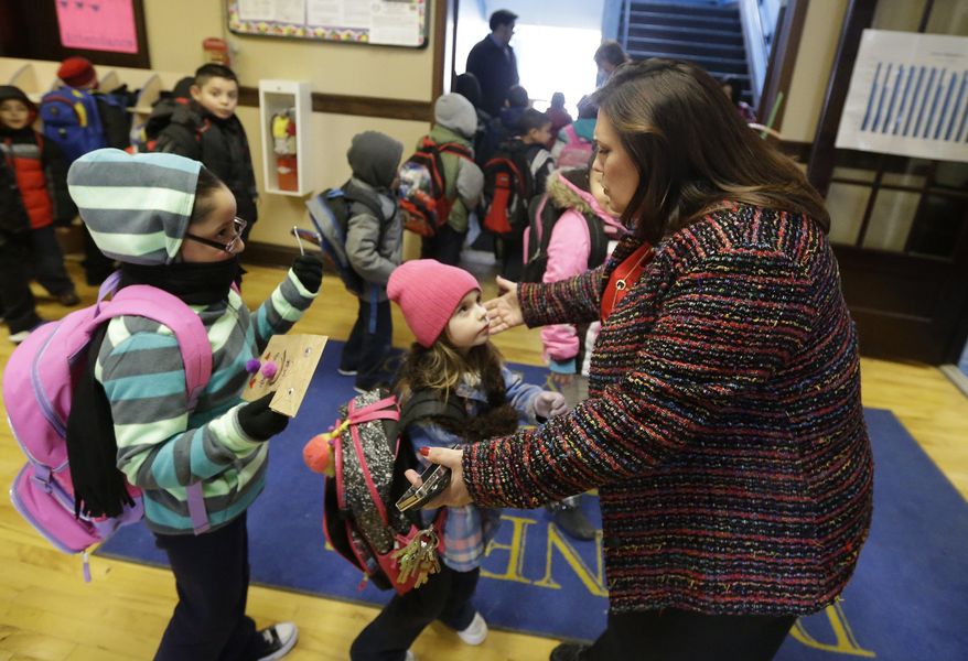 ADVANCE FOR USE SUNDAY, MARCH 23, 2014 AND THEREAFTER - In this Feb. 26, 2014 photo, Bennett Elementary School Principal Josette Buendia receives hugs from her students at the end of the school day in Detroit. Buendia couples fun - such as a weekly "Popcorn Friday" - with academic innovations, including one-on-one tutoring for her 4th and 5th graders via Skype with student volunteers at a suburban high school. (AP Photo/Carlos Osorio)