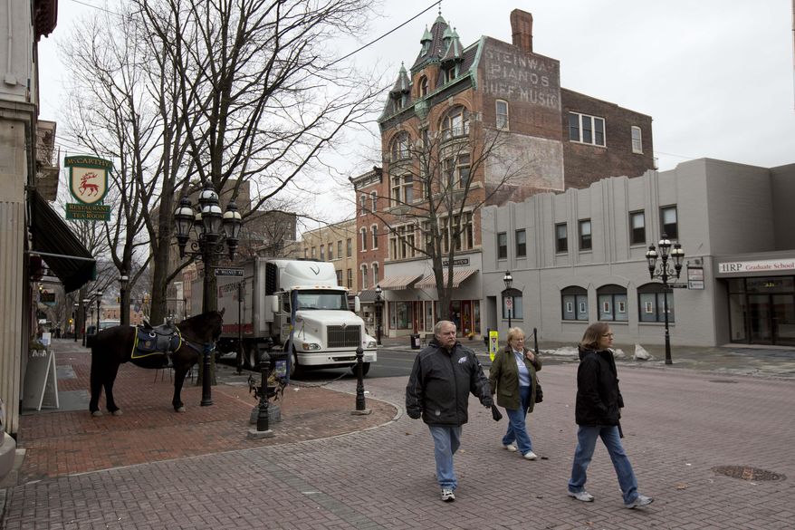 People walk in an area slated for improvements Wednesday, March 19, 2014, in Bethlehem, Pa. The city will delay a downtown streetscape project that would replace slate and brick sidewalks, urns, benches and trees, public works director Mike Alkhal said. The city has no choice after more than doubling its usual spending on winter maintenance, including a hefty overtime bill for road crews. (AP Photo/Matt Rourke)