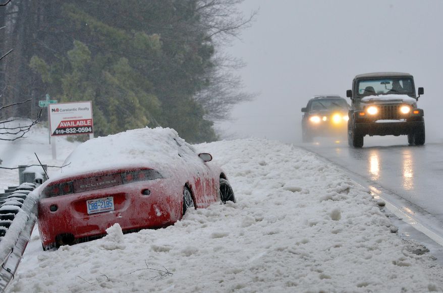 FILE - In this Feb. 13, 2014 file photo vehicles pass an abandoned car following a storm that brought snow, sleet and freezing rain to Raleigh, N.C. As spring officially begins Thursday, officials across much of the nation are still paying the bills for keeping roads clear during the cold, snowy winter. North Carolina planned for $40 million and has spent $62 million. (AP Photo/The News & Observer, Chuck Liddy, File)