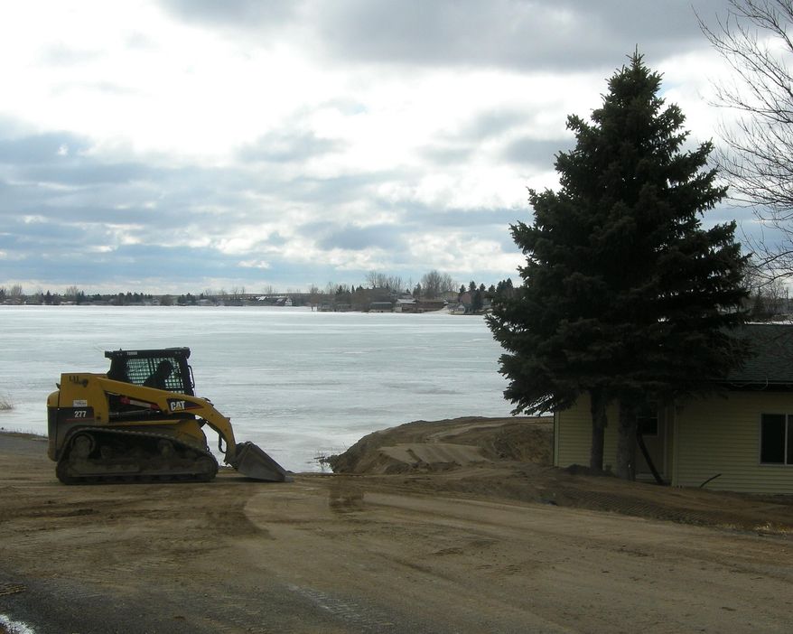 A property owner shores up a dike to ensure protection against the rising of Rice Lake on March 19, 2014 in Minot, N.D. Property owners around Rice Lake in north central North Dakota are once again battling floods, and some are giving up the fight. The lake where 167 people own property and 36 of them live year-round has risen 12 inches in 12 days because of snowmelt, according to Rice Lake Board Chairman Steve Zaun. It is the fourth straight year of flooding, and the lake has now damaged or destroyed about 30 homes. (AP Photo/The Minot Daily News, Jill Schramm)