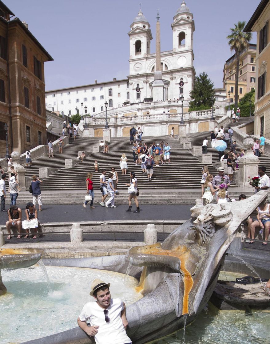 FILE - In this Wednesday, June 20, 2012 file photo, a tourists cools off in the 17th-century Bernini fountain, also known as Barcaccia, in front of the historical Spanish Steps in Rome. Rome's iconic Spanish Steps are getting a makeover. High-end jeweler Bulgari is donating 1.5 million euros ($2 million) to the city of Rome to restore the staircase that connects the swank Piazza di Spagna with the Trinita dei Monti church above. It's the latest Italian luxury brand to step in to spruce up Rome's historic landmarks as public funding dips: Shoemaker Tod's has put up 25 million euros to restore the Colosseum while fashion house Fendi is taking care of Rome's fountains. The restoration announced Thursday, March 20, 2014, involves cleaning the travertine steps, removing plants that have sprung up in cracks and repairing steps that have been chipped since the last major renovation in 1995. Bulgari, whose flagship store is just down the street, offered the funding to mark its 130th anniversary. (AP Photo/Andrew Medichini, File)