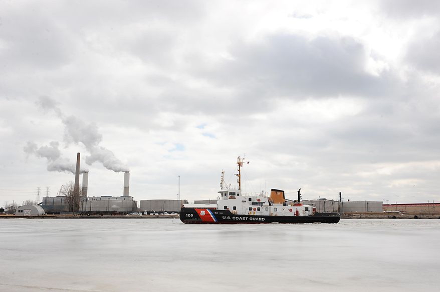 The U.S. Coast Guard ice cutter Neah Bay breaks up ice on the River Raisin in the turning basin at the Port of Monroe Thursday, March 20, 2014, in Monroe, Mich. In the background is DTE Energy of Monroe. (AP Photo/The Monroe News, Tom Hawley)