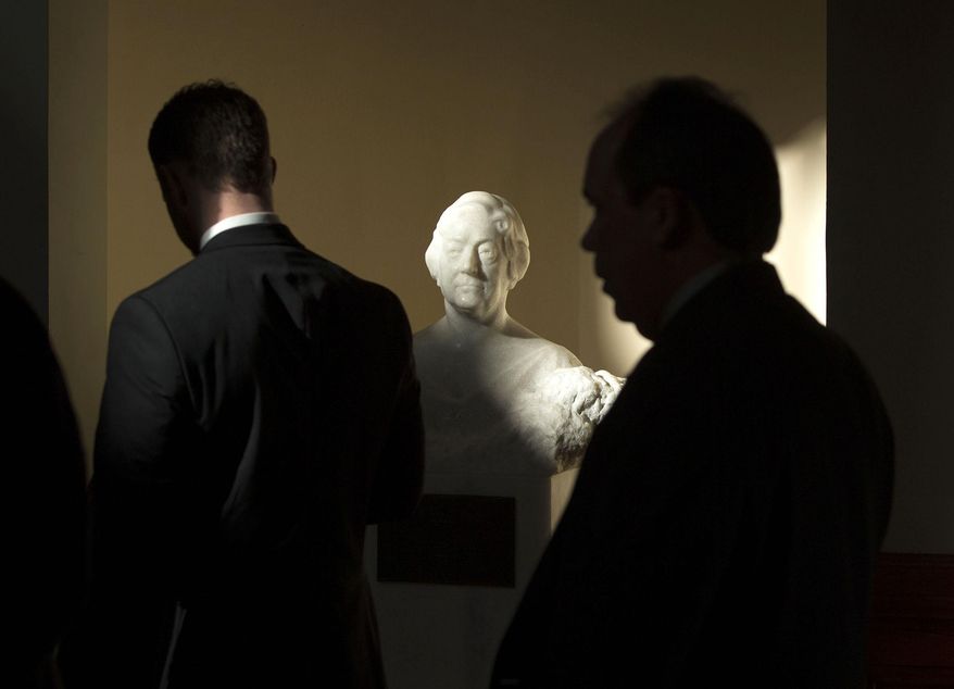 The sun shines on a statue of Moina Bell Michael, center, as lobbyists walk by on the last day of the legislative session at the Georgia State Capitol, Thursday, March 20, 2014, in Atlanta. Georgia lawmakers face a tough to-do list on the final day of the 2014 legislative session, with final decisions still needed on issues ranging from where Georgians can legally carry guns to whether cancer patients and others with illnesses can legally take a form of medical marijuana. (AP Photo/Jason Getz)