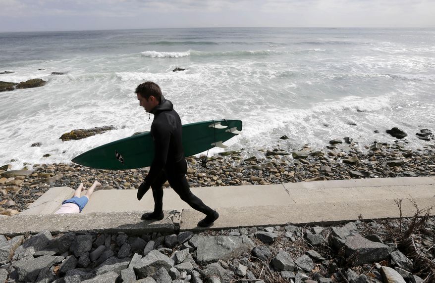 Michael Ferreira, of Newport, R.I., carries his surfboard on a seawall along the coast, on the first day of spring Thursday, March 20, 2014, in Newport. As much of the United States remained in a deep freeze, government forecasters Thursday predicted temperatures will be below normal this spring across the northern U.S. (AP Photo/Steven Senne)