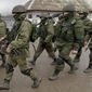 Pro-Russian soldiers march outside an Ukrainian military base in Perevalne, Crimea, Thursday, March 20, 2014. With thousands of Ukrainian soldiers and sailors trapped on military bases, surrounded by heavily armed Russian forces and pro-Russia militia, the Kiev government said it was drawing up plans to evacuate its outnumbered troops from Crimea back to the mainland and would seek U.N. support to turn the peninsula into a demilitarized zone.(AP Photo/Vadim Ghirda)