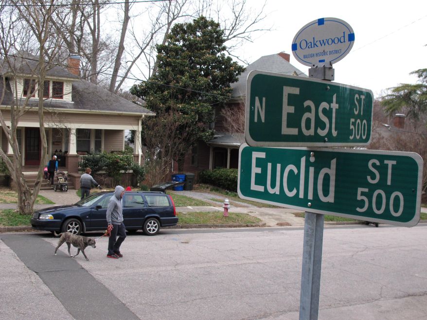 A man walks his dog along East Street in the Historic Oakwood neighborhood of Raleigh, N.C., on Sunday, March 16, 2014. The city is going to court over a ruling that a modern-styled home under construction doesn't fit with in this enclave of bungalows, shotgun houses and Victorians. (AP Photo/Allen G. Breed)