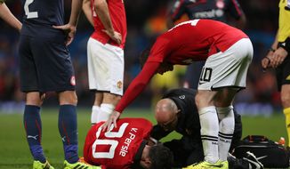 Manchester United&#39;s Robin van Persie, bottom, lies injured after colliding with Olympiakos&#39;s Kostas Manolas during their  Champions League last 16 second leg soccer match at Old Trafford Stadium, Manchester, England, Wednesday, March 19, 2014. (AP Photo/Jon Super)