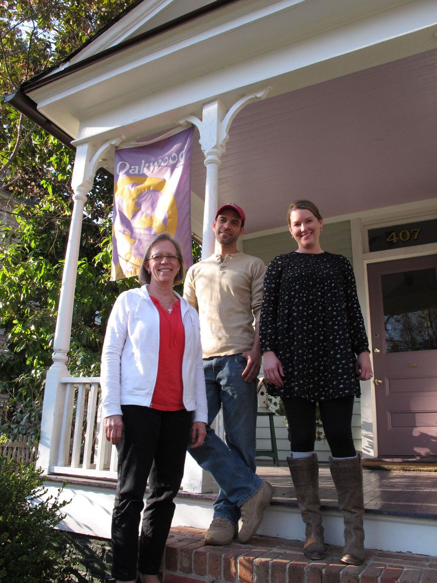 From left, Mary Iverson, Will Hillebrenner and Heather Scott stand on the porch of a Victorian home in the Historic Oakwood neighborhood of Raleigh, N.C., on Thursday, March 20, 2014. The three are among the opponents of a modern house that they believe doesn't fit in with the district's historic aesthetic. Iverson, who owns four historic homes in the neighborhood, says the Cherry house is beautiful, but it doesn't belong in Oakwood. "That is a leap of 100 years of design architecture," she says. "So that's not an evolution. That's a, 'So let's go to another planet.'" (AP Photo/Allen G. Breed)