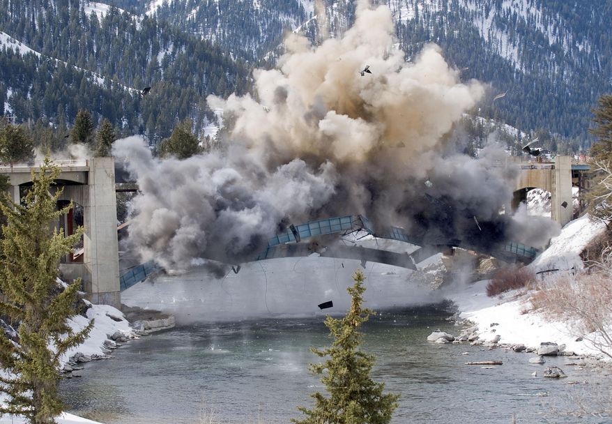 The steel arch of the old Hoback Bridge, just south of Jackson, Wyo., crumbles into the Snake River after demolition crews used explosives to destroy the structure Thursday, March 20, 2014. The Wyoming Department of Trasportation will spend the next several days fishing the debris out of the river. (AP Photo / Jackson Hole News&Guide, Bradly J. Boner)