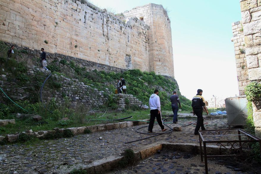 People walk around the Crac des Chevaliers as Syrian troops take reporters on a tour a day after they ousted rebels from the castle located near the village of Hosn, Syria, Friday, March 21, 2014. The Syrian army ousted rebels from the massive Crusader fortress after several hours of fierce fighting, killing at least 93 of them as they fled to neighboring Lebanon, an army commander told reporters on a government-led tour of the area Friday. (AP Photo)