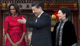 Chinese President Xi Jinping, center, and his wife Peng Liyuan, right, show the way to U.S. first lady Michelle Obama as they proceed to a meeting room at the Diaoyutai state guesthouse in Beijing, China Friday, March 21, 2014. (AP Photo/Andy Wong, Pool)