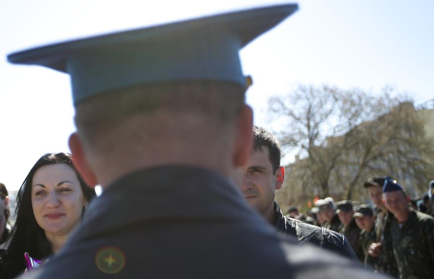 Colonel Yuly Mamchur, center, speaks to Lieutenants Galina Volosyanchik, left, and Ivan Benera, center right, celebrating their wedding at the Belbek airbase outside Sevastopol, Crimea, on Saturday, March 22, 2014. Two young Lieutenants got married today and arrived to their unit for a short celebration as Russian troops continue to occupy part of the airbase and demand surrender of Ukrainian airmen. (AP Photo/Ivan Sekretarev)