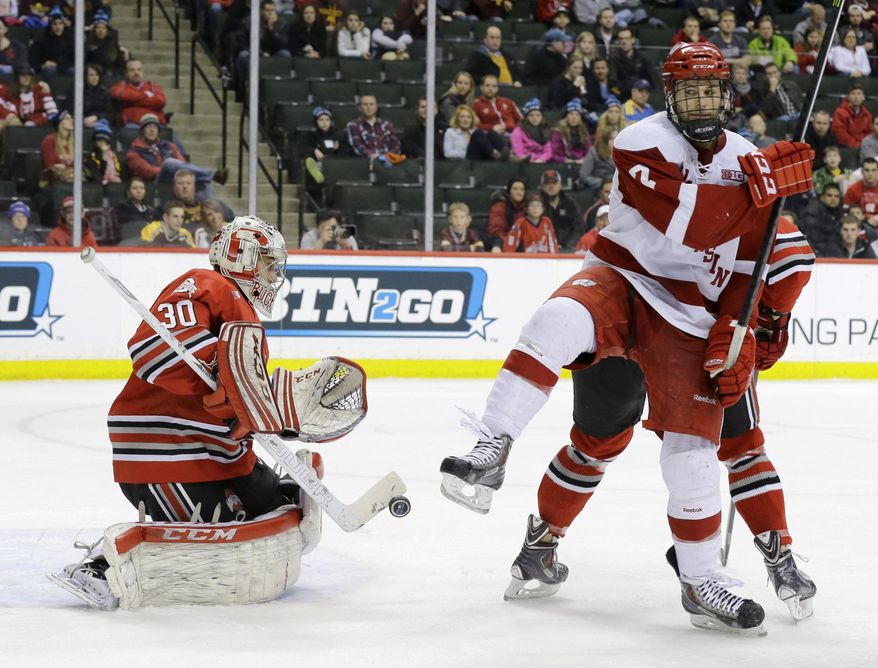 Ohio State goalie Christian Frey (30) deflects a shot as Wisconsin forward Tyler Barnes, right, jumps out of the way during the second period of the championship college hockey game of the Big 10 Conference tournament in St. Paul, Minn., Saturday, March 22, 2014. (AP Photo/Ann Heisenfelt)