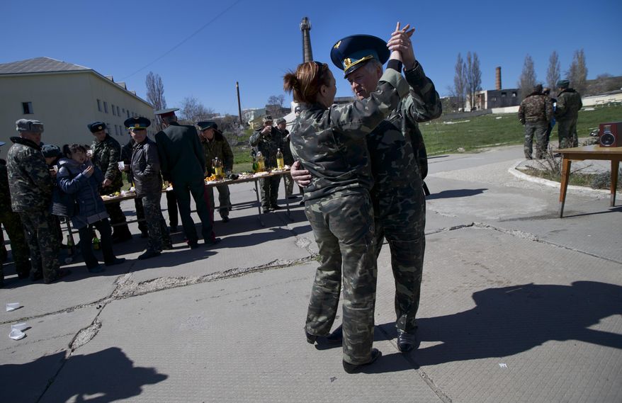 Ukrainian airmen dance as they celebrate their comrade's wedding at the Belbek airbase outside Sevastopol, Crimea, on Saturday, March 22, 2014. Two young Lieutenants, medic Galina Volosyanchik and communication officer Ivan Benera got married today and arrived to their unit for a short celebration as Russian troops continue to occupy part of the airbase and demand surrender of Ukrainian airmen. (AP Photo/Ivan Sekretarev)