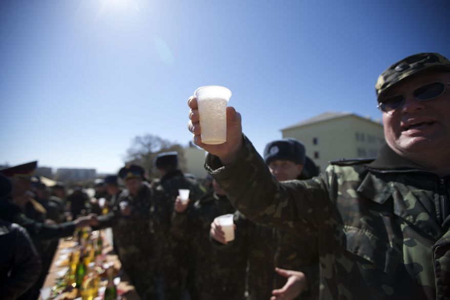 A Ukrainian officer raises a cup to toast his comrade's wedding at the Belbek airbase outside Sevastopol, Crimea, on Saturday, March 22, 2014. Two young Lieutenants, medic Galina Volosyanchik and communication officer Ivan Benera got married today and arrived to their unit for a short celebration as Russian troops continue to occupy part of the airbase and demand surrender of Ukrainian airmen. (AP Photo/Ivan Sekretarev)