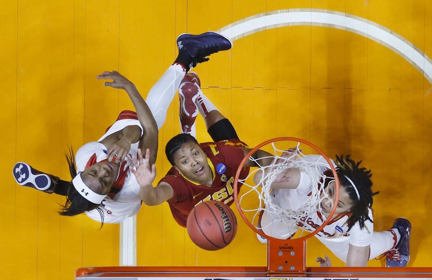 Southern California guard Ariya Crook, center, shoots as she is defended by St. John's Aliyyah Handford, left, and Selina Archer, right, in the first half of an NCAA women's college basketball first-round tournament game, Saturday, March 22, 2014, in Knoxville, Tenn. (AP Photo/Mark Humphrey)