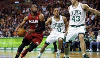 Miami Heat guard Dwyane Wade (3) drives against Boston Celtics guard Avery Bradley (0) and center Kris Humphries (43) in the first quarter of an NBA basketball game in Boston on Wednesday, March 19, 2014. (AP Photo/Elise Amendola)