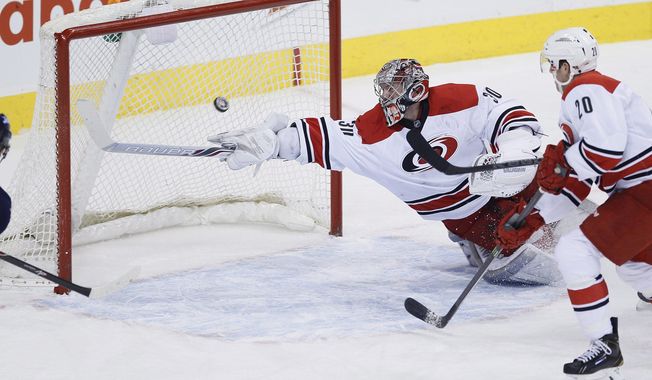 Carolina Hurricanes goaltender Cam Ward (30) sticks-saves the shot from Winnipeg Jets&#x27; Bryan Little as Hurricanes&#x27; Riley Nash (20) watches during the first period of an NHL hockey game, Saturday, March 22, 2014, in Winnipeg, Manitoba. (AP Photo/The Canadian Press, John Woods)