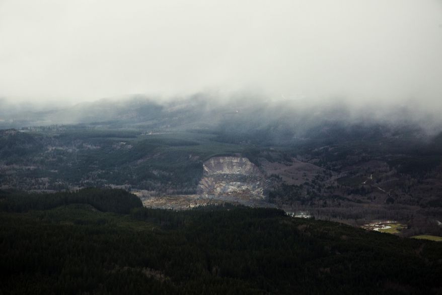 A wide aerial view shows a huge volume of earth missing from the side of a hill facing the Stillaguamish River, in a landslide along State Route 530, between the cities of Arlington and Darrington, on Saturday, March 22, 2014. Search and rescue operations are underway for survivors. (AP Photo/ The Seattle Times, Marcus Yam ) MANDATORY CREDIT TO: Marcus Yam / THE SEATTLE TIMES.