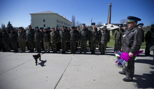 Colonel Yuly Mamchur, right, holds flowers as other Ukrainian airmen line up to greet their comrades who arrived to celebrate their wedding at the Belbek airbase outside Sevastopol, Crimea, on Saturday, March 22, 2014. Two young Lieutenants, medic Galina Volosyanchik and communication officer Ivan Benera got married today and arrived to their unit for a short celebration as Russian troops continue to occupy part of the airbase and demand surrender of Ukrainian airmen. (AP Photo/Ivan Sekretarev)
