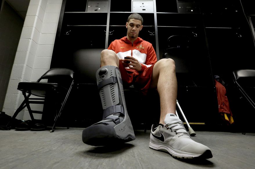 Iowa State's Georges Niang looks at his phone as he sits in the locker room before an NCAA college basketball tournament practice Saturday, March 22, 2014, in San Antonio. Niang, who broke his foot during Friday's game against North Carolina Central, with not play when Iowa State plays North Carolina Sunday. (AP Photo/David J. Phillip)
