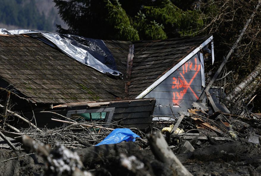The orange X on a house, destroyed in the mud, indicates it has been searched for people on Highway 530, Sunday, March 23, 2014 the day after a giant landslide occurred near Oso, Wash. Rescue crews searched into the night for survivors from a massive mudslide that killed at least three people, after hearing voices from the debris field pleading for help. (AP Photo/The Seattle Times, Lindsey Wasson, Pool)