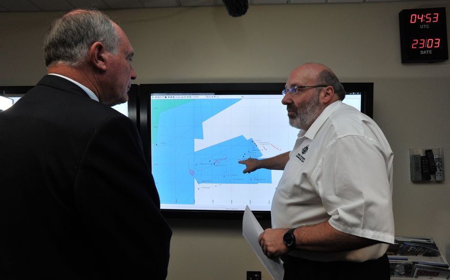 Mike Barton, rescue coordination chief, right, shows Australia's Deputy Prime Minister, Warren Truss, the map of the Indian Ocean search areas at the rescue coordination center of Australian Maritime Safety Authority in Canberra, Sunday, March 23, 2014. Planes and ships scrambled Sunday to find a pallet and other debris in a remote patch of the southern Indian Ocean to determine whether the objects were from the Malaysia Airlines jet that has been missing for more than two weeks. (AP Photo/Graham Tidy, Pool)