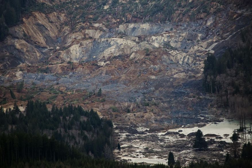 An aerial view shows a huge volume of earth missing from the side of a hill facing Stillaguamish River, in a landslide along State Route 530, between the cities of Arlington and Darrington, on Saturday, March 22, 2014. Search and rescue operations are underway for survivors. (AP Photo/ The Seattle Times, Marcus Yam) MANDATORY CREDIT TO BOTH THE SEATTLE TIMES AND THE PHOTOGRAPHER