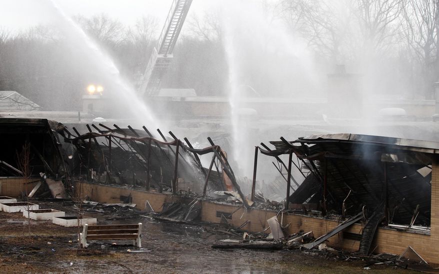 Firefighters spray the ruins at James Monroe School, following a fire at the school in Edison Township, N.J., Sunday, March 23, 2014. The fire began Saturday night, and district officials met Sunday afternoon to develop a plan for the affected children. (AP Photo/Home News Tribune, Jason Towlen) NEWARK OUT; NO SALES; NEWARK STAR LEDGER OUT