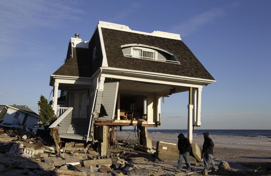 ADVANCE FOR USE MONDAY, MARCH 24, 2014 AT 3 A.M. AND THEREAFTER - FILE - In this Dec. 5, 2012 file photo, men walk past a house damaged during Superstorm Sandy in the Belle Harbor section of the Queens borough of New York. While President Barack Obama signed a law Friday, March 21, 2014 that will delay steep increases to flood insurance paid by many, nearly 60,000 policyholders in New York state are among the 1.1 million nationwide who will see their federally subsidized flood insurance premiums rise as part of changes to the National Flood Insurance Program, according to a review of federal data by The Associated Press. (AP Photo/Kathy Willens, File)