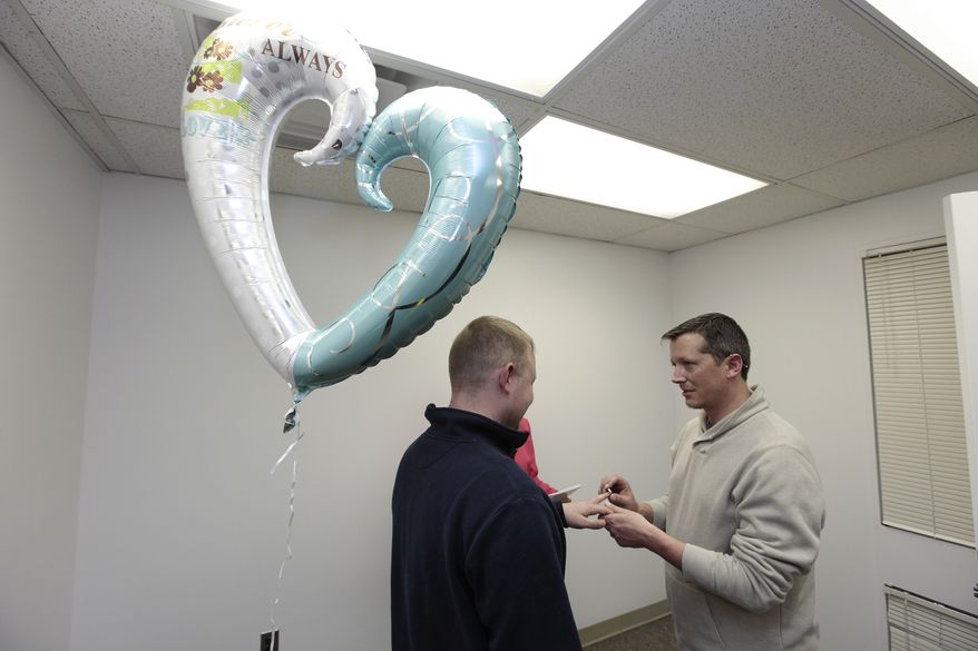 Josh Redder, right, puts a wedding ring on parter Justin Flowers, while being married at the Oakland County Clerks office in Pontiac, Mich., Saturday, March 22, 2014. A federal judge has struck down Michigan's ban on gay marriage Friday the latest in a series of decisions overturning similar laws across the U.S. Some counties plan to issue marriage licenses to same-sex couples Saturday, less than 24 hours after a judge overturned Michigan's ban on gay marriage. (AP Photo/Paul Sancya)
