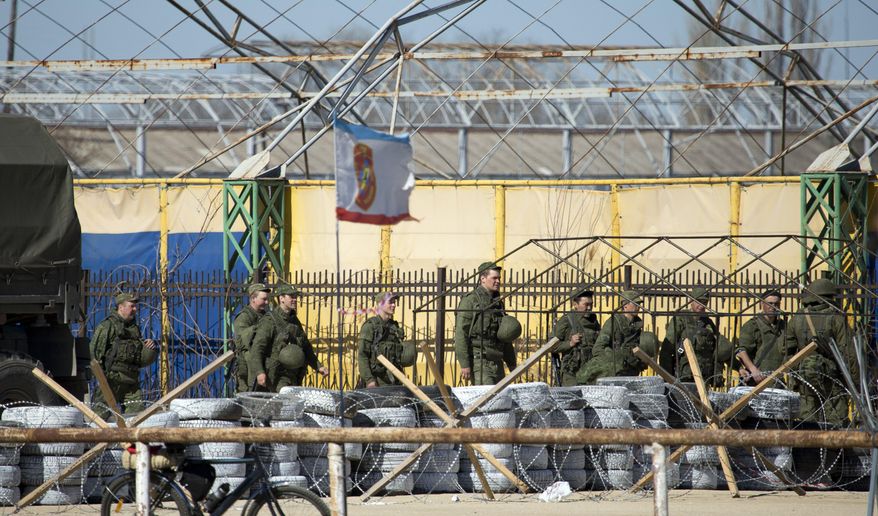 Soldiers in unmarked uniforms walk near Ukrainian marine base in the city of Feodosia, Crimea, Sunday, March 23, 2014. On Sunday, the Russian Defense Ministry said the Russian flag was now flying over 189 military facilities in Crimea. It didn't specify whether any Ukrainian military operations there remained under Ukrainian control. (AP Photo/ Pavel Golovkin)