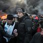 Opposition leader and former WBC heavyweight boxing champion Vitali Klitschko, center, addresses protesters near the burning barricades between police and protesters in central Kiev, Ukraine, Thursday Jan. 23, 2014.  Klitschko dove behind the wall of black smoke engulfing much of downtown Kiev on Thursday, pleading with both police and protesters to uphold the peace until the ultimatum, demanding that Yanukovych dismiss the government, call early elections and scrap harsh anti-protest legislation that triggered the violence. (AP Photo/Sergei Chuzavkov)