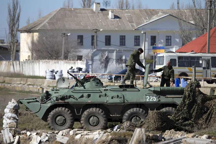 Pro-Russian soldiers in unmarked uniforms arrange a position on top an APC near Ukrainian marines base in the city of Feodosia, Crimea, Sunday, March 23, 2014. On Sunday, the Russian Defense Ministry said the Russian flag was now flying over 189 military facilities in Crimea. It didn't specify whether any Ukrainian military operations there remained under Ukrainian control. (AP Photo/ Pavel Golovkin)