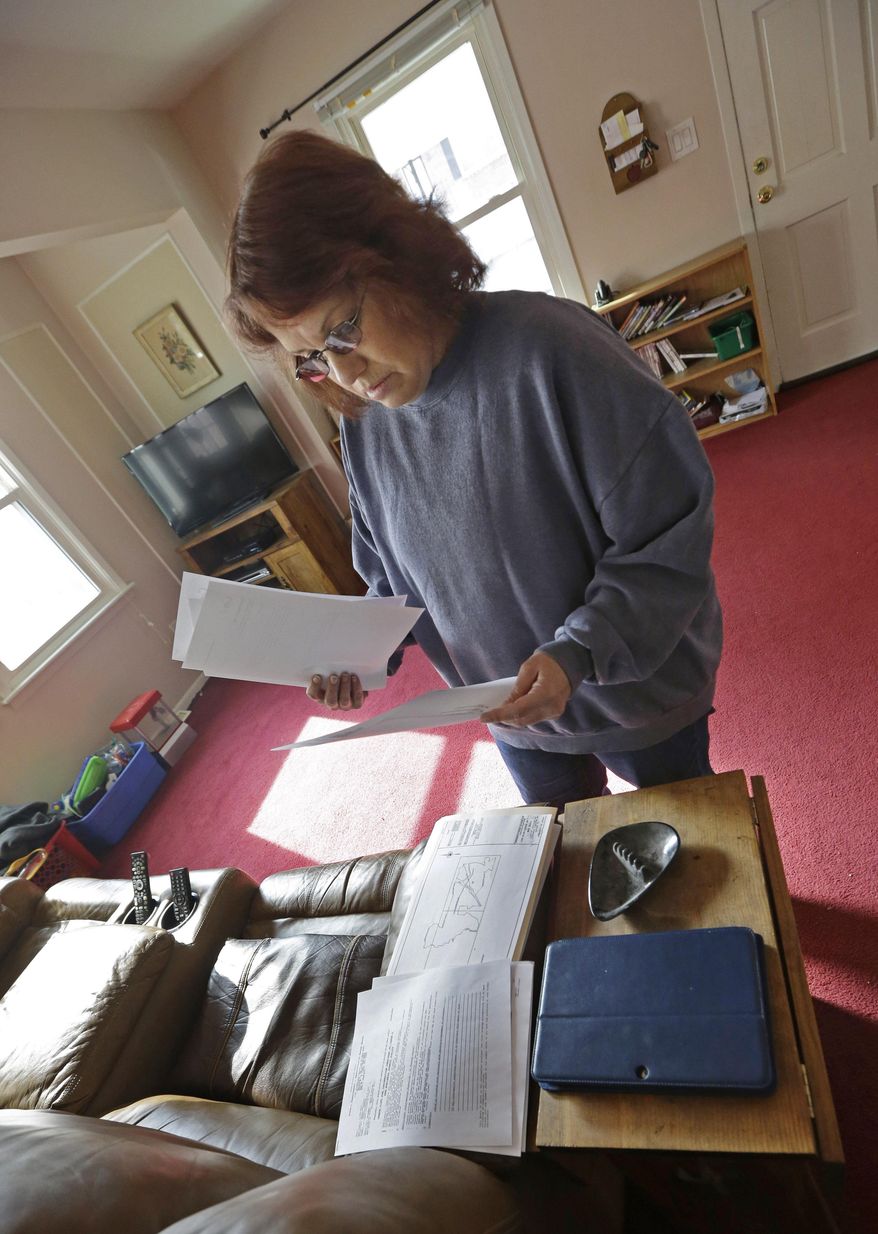 ADVANCE FOR USE MONDAY, MARCH 24, 2014 AT 3 A.M. AND THEREAFTER - Regina Bachman looks through papers dealing flood insurance on her property inside her home in Loveland, Ohio on Friday, March 21, 2014. Bachman bought the home in September 2013 and was initially told by the bank that flood insurance on the property would be affordable, only to find out after closing that the rates were going to increase over $7,000 more annually with new premiums for the National Flood Insurance Program. (AP Photo/Al Behrman)