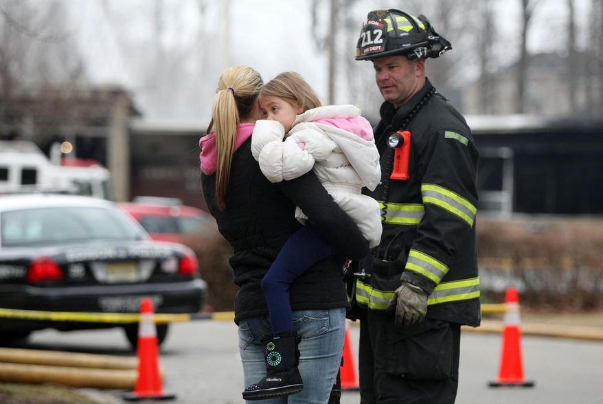 Alexis Spagnoli holds her daughter Adriana, a kindergarten student at the James Monroe School, while speaking to Edison firefighter John Kantra following a fire at the school in Edison Township, N.J., Sunday, March 23, 2014. The fire began Saturday night, and district officials met Sunday afternoon to develop a plan for the affected children. (AP Photo/Home News Tribune, Jason Towlen) NEWARK OUT; NO SALES; NEWARK STAR LEDGER OUT