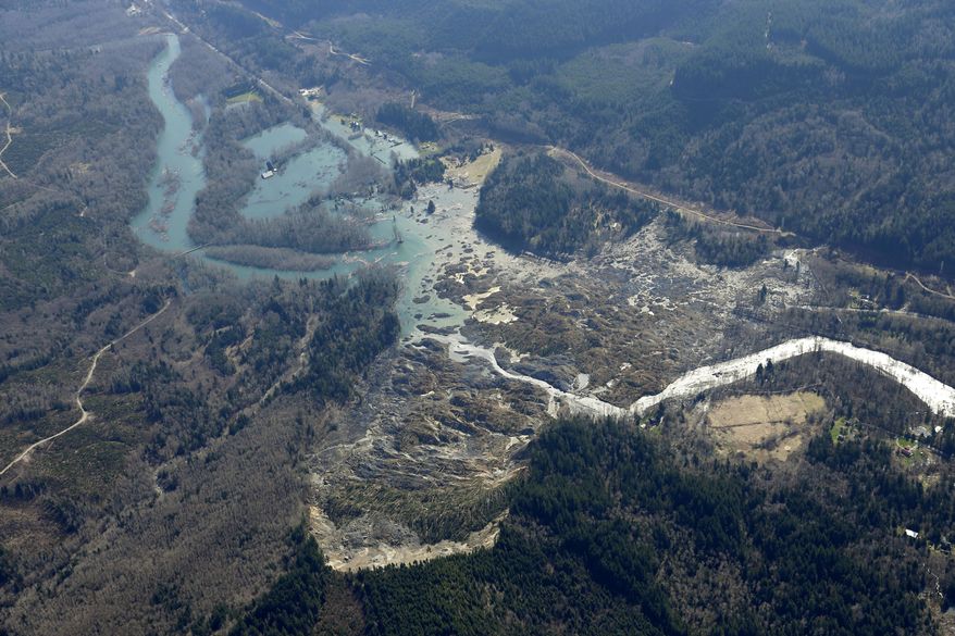 The Stillaguamish River is shown backed up at left in this aerial photo Monday, March 24, 2014, near Arlington, Wash., after it was blocked on Saturday by the massive mudslide shown at center, that killed at least eight people and left dozens missing, The search for survivors grew Monday raising fears that the death toll could climb far beyond the eight confirmed fatalities. (AP Photo/Ted S. Warren)