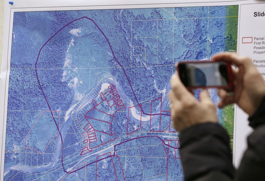 A news person photographs a map showing the location of a deadly mudslide that happened two days earlier, before a news conference, Monday, March 24, 2014, in Arlington, Wash. Officials said that there are currently 108 names of people who have been reported missing or are unaccounted for from the Saturday morning slide, but cautioned the figure would likely decline dramatically. Eight people are so far confirmed dead from the one-square mile slide that destroyed about 30 homes and critically injured several people. (AP Photo/Elaine Thompson)
