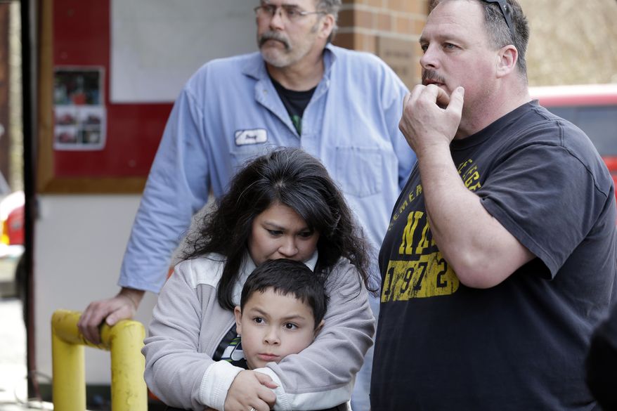 Eveleen Promise holds her son, Xaven, 7, and stands with her husband Patrick Belt, right, and Doug Massingale stands behind as they all wait for word of missing family members at the fire station in Oso, Wash., following a deadly mudslide two days earlier Monday, March 24, 2014. Officials said that there are currently 108 names of people who have been reported missing or are unaccounted for from the Saturday morning slide, but cautioned the figure would likely decline dramatically. Eight people are so far confirmed dead from the one-square mile slide that destroyed about 30 homes and critically injured several people. (AP Photo/Elaine Thompson)