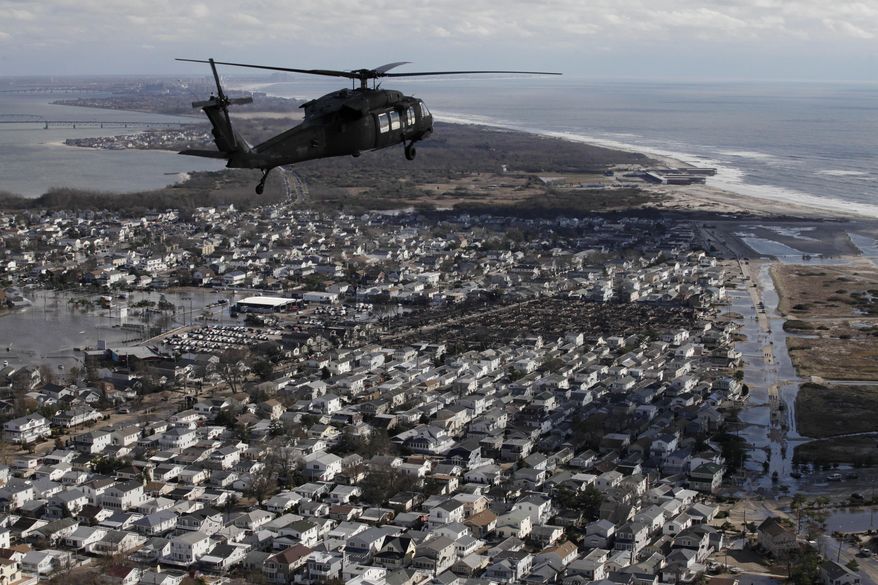 In this Oct. 31, 2012 aerial photo, a New York Air National Guard helicopter with Gov. Andrew Cuomo aboard flies over the ocean side community of Breezy Point in the Queens borough of New York to survey the damage caused by Superstorm Sandy. While President Barack Obama signed a law Friday, March 21, 2014 that will delay steep increases to flood insurance paid by many, nearly 60,000 policyholders in New York state are among the 1.1 million nationwide who will see their federally subsidized flood insurance premiums rise as part of changes to the National Flood Insurance Program, according to a review of federal data by The Associated Press. (AP Photo/Mark Lennihan)