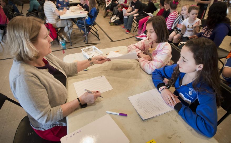 Christina Varo, left, checks documentation for "immigrants" Paige Bishop, right, and Katie Kime during a school project simulating the Ellis Island experience Monday, March 10, 2014, at ABC-Stewart School in Columbus, Ind. The students learned what the process would have been like a century ago if they had to travel through Ellis Island. (AP Photo/The Republic, Andrew Laker)