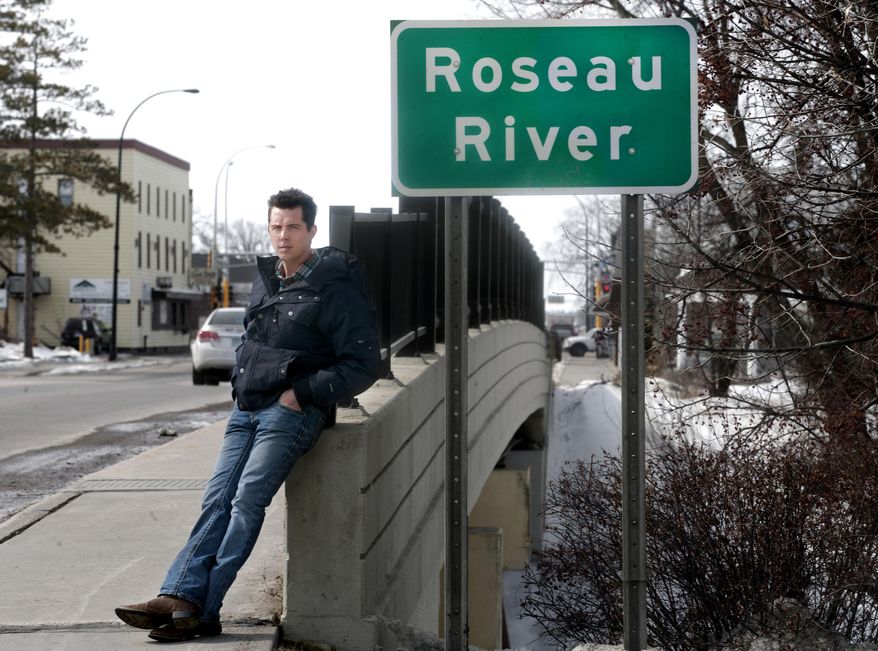 Bob Brellenthin of Pahlen Realty stands at a bridge crossing the Roseau River in Roseau, Minn. on Thursday, March 20, 2014. He knows first hand the effect the new, higher national flood insurance premiums have had on his business and the difficulty his customers have had selling their homes because of the changes in the National Flood Insurance Program. (AP Photo/Bruce Crummy)