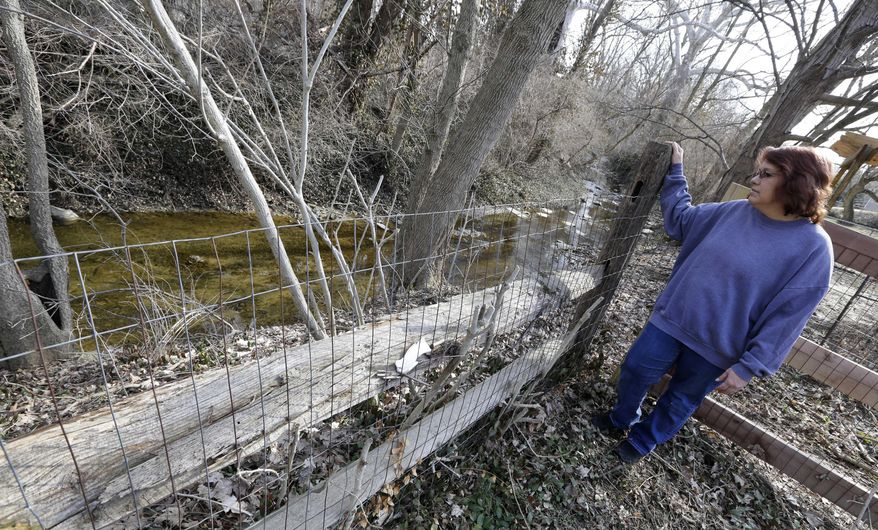 Regina Bachman looks down at a small creek running behind her home in Loveland, Ohio on Friday, March 21, 2014. Bachman bought the home in September 2013 and was initially told by the bank that flood insurance on the property would be affordable, only to find out after closing that the rates were going to increase over $7,000 more a year with new premiums for the National Flood Insurance Program. (AP Photo/Al Behrman)