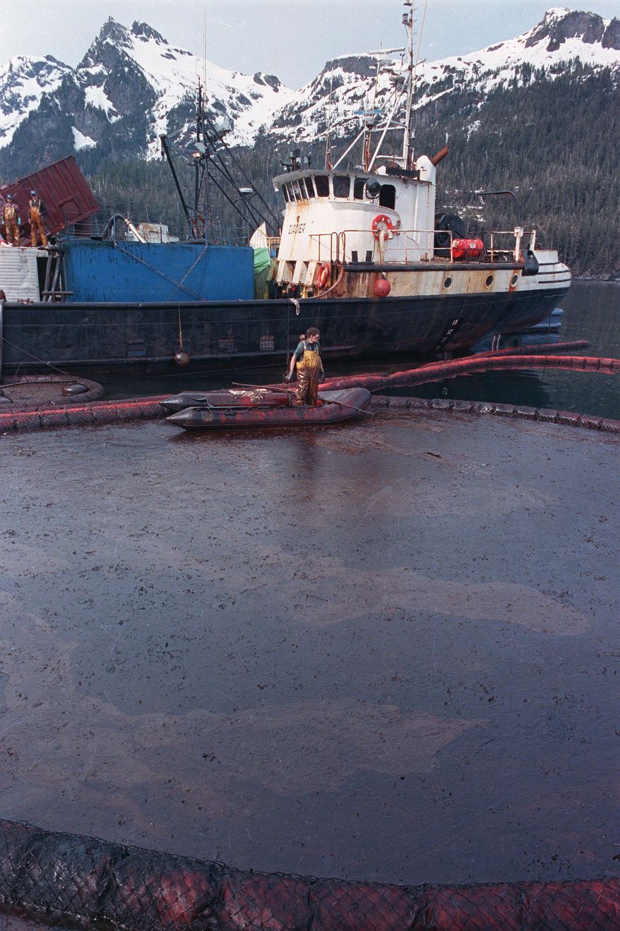 FILE - In this April 16, 1989, file photo, a clean-up worker rakes through crude oil, contained by floating booms off the waters of Prince William Sound, Alaska. The oil, contained here in Snug Harbor off Knight Island, was later sucked off the water by a U.S. Coast Guard skimmer. Oil from the tanker Exxon Valdez continues to foul the waters of southern Alaska. Nearly 25 years after the Exxon Valdez oil spill off the coast of Alaska, some damage heals, some effects linger in Prince William Sound. (AP Photo/John Gaps III, File)