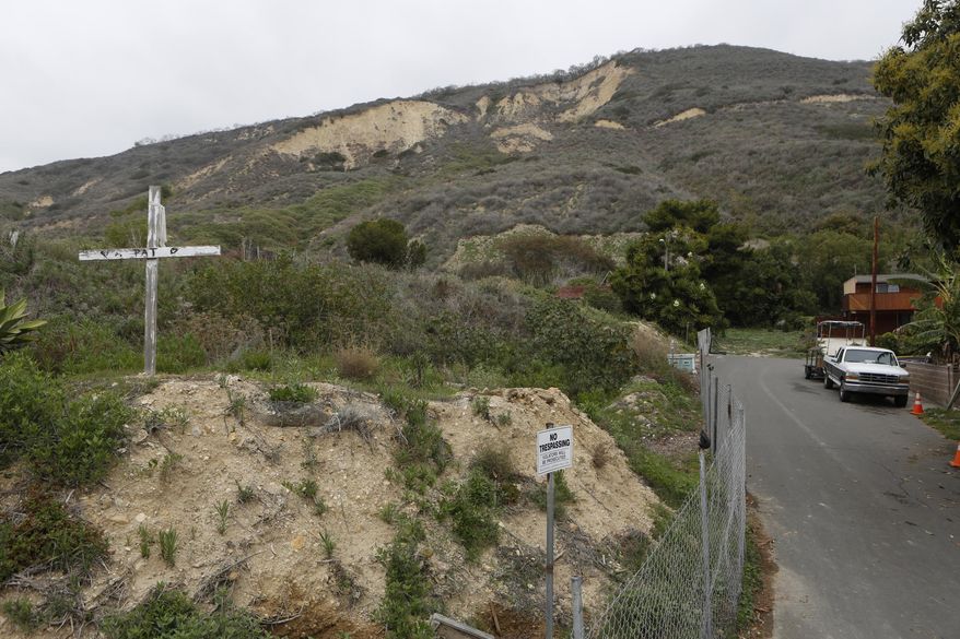 A cross marks a fenced home buried by a mudslide in the tiny coastal town of La Conchita, Calif., on Monday, March, 24, 2014. As with Oso, Wash., the coastal Southern California town of La Conchita knows the sorrows that a major mudslide can unleash. In 2005, a wall of debris slammed down from a bluff soaked by winter storms, killing 10 people and damaging or destroying 36 homes. (AP Photo/Damian Dovarganes)
