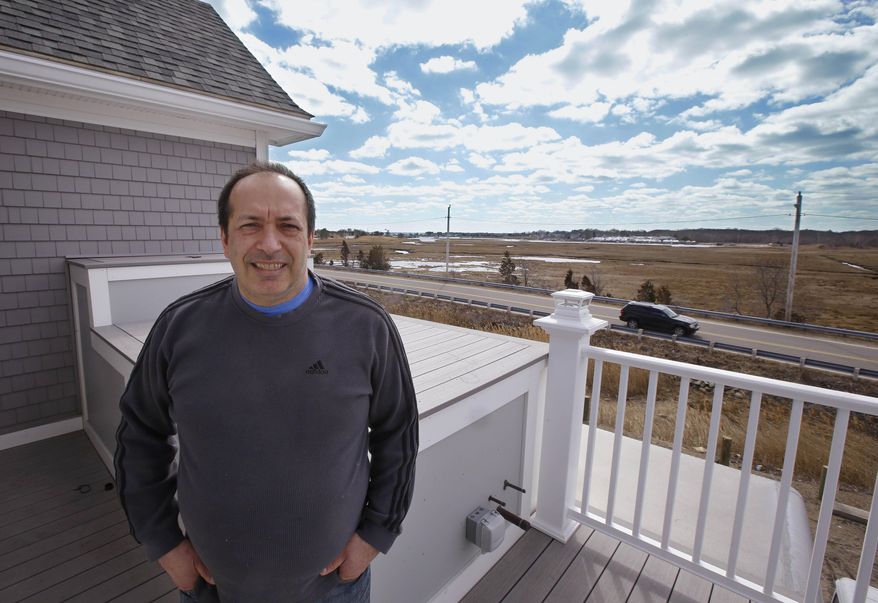 Mitch Haddad stands on a second story balcony that overlooks marshlands and the harbor beyond at his restaurant, Haddad's Ocean Cafe, in the Brant Rock area of Marshfield, Mass., Friday, March 21, 2014. The restaurant has been in his family for over 70 years. When they decided to build a larger building recently, FEMA said the structure must be at least 11 feet off the ground. So they decided to go higher, building at 13 feet. About a year after the new restaurant opened, Mitch Haddad said they were told new federal flood maps now put the safe elevation at 16 feet. (AP Photo/Stephan Savoia)
