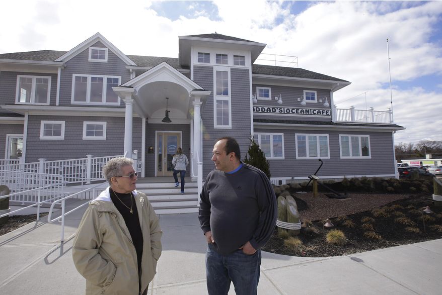 Mitch Haddad, right, talks with a patron outside his restaurant, Haddad's Ocean Cafe, after lunch in the Brant Rock area of Marshfield, Mass., Friday, March 21, 2014. The restaurant has been in his family for over 70 years. When they decided to build a larger building recently, FEMA said the structure must be at least 11 feet off the ground. So they decided to go higher, building at 13 feet. About a year after the new restaurant opened, Mitch Haddad said they were told new federal flood maps now put the safe elevation at 16 feet. (AP Photo/Stephan Savoia)
