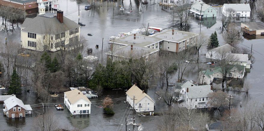 FILE - In this March 31, 2010 file photo, water encircles homes from the flooded Pawtuxet River in West Warwick, R.I. In 2012, Congress passed a law requiring approximately 1.1 million policyholders nationwide to start paying rates based on the true risk of flooding. Nearly 7,000 Rhode Island homeowners and businesses could see their flood insurance premiums rise annually by double digit percentages as government-backed insurance subsidies are scaled back, according to an Associated Press analysis of data from the National Flood Insurance Program. (AP Photo/Charles Krupa, File)