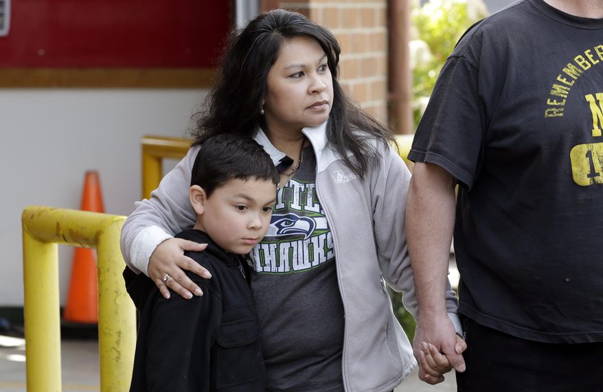 Eveleen Promise holds her son, Xaven, 7, as they wait for word of missing family members at the fire station in Oso, Wash., following a deadly mudslide two days earlier Monday, March 24, 2014. Officials said that there are currently 108 names of people who have been reported missing or are unaccounted for from the Saturday morning slide, but cautioned the figure would likely decline dramatically. Eight people are so far confirmed dead from the one-square mile slide that destroyed about 30 homes and critically injured several people. (AP Photo/Elaine Thompson)