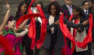 U.S. first lady Michelle Obama, center, dances with performers during her visit to an ancient city wall with her daughters Malia, second from left, and Sasha, right, in Xi&#39;an, in northwestern China&#39;s Shaanxi province, Monday, March 24, 2014. (AP Photo/Alexander F. Yuan)
